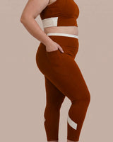 Side view of Brown High-Rise Leggings with a hand tucked into the deep side pocket.