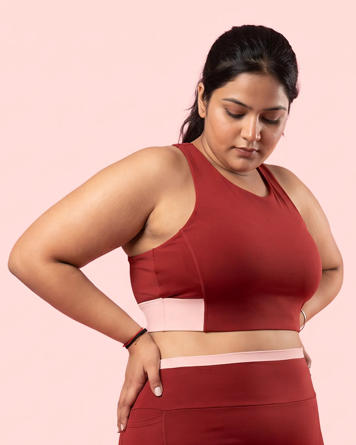 Model in the Maroon Full Coverage Sports Bra with a hand on her hip, showing the full coverage fit on a fuller bust.