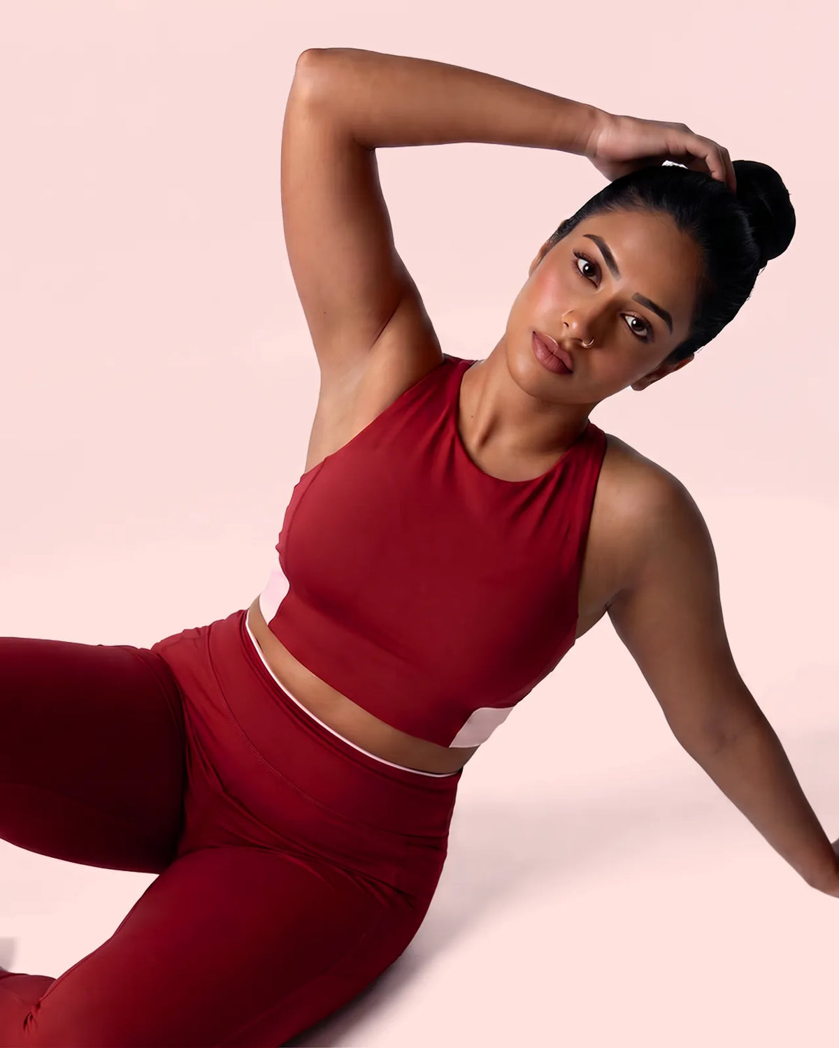 Model lying on her side in the Maroon Full Coverage Sports Bra and leggings, one hand behind her head.