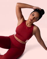 Model lying on her side in the Maroon Full Coverage Sports Bra and leggings, one hand behind her head.