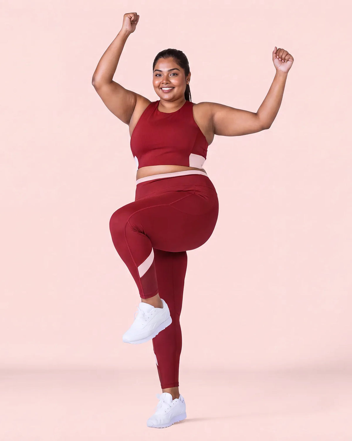 Woman mid-dance with one knee raised and arms up, wearing the Maroon Full Coverage Sports Bra and High-Rise Leggings.