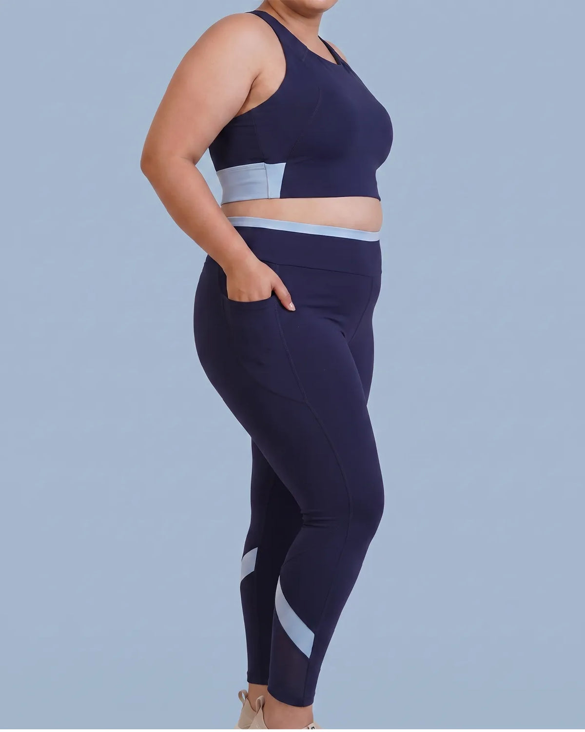 Side view of Navy High-Rise Leggings with a hand tucked into the deep side pocket.