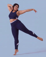 Woman mid-dance with one leg extended behind her and arms outstretched, wearing the Navy Full Coverage Sports Bra and High-Rise Leggings.