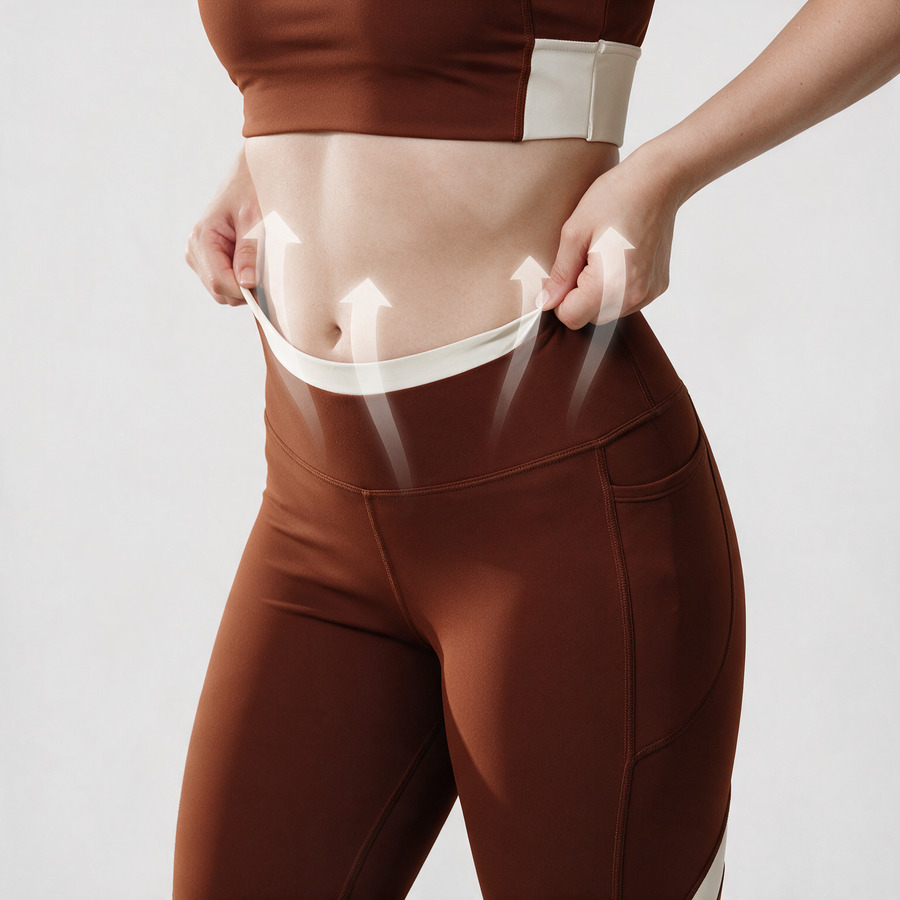 Woman lifting the cream waistband of brown leggings, with arrows showing how it holds at the waist.