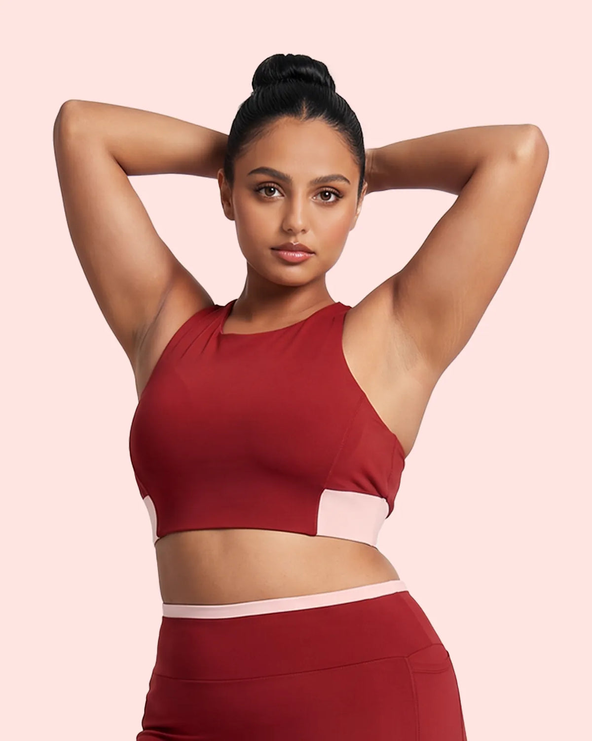 Front view of the Maroon Full Coverage Sports Bra with a blush pink underband, model's hands behind her head.