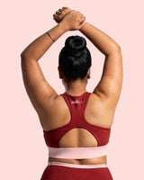 Back view of the Maroon Full Coverage Sports Bra, showing the racerback construction and wide underband, model's arms raised overhead.