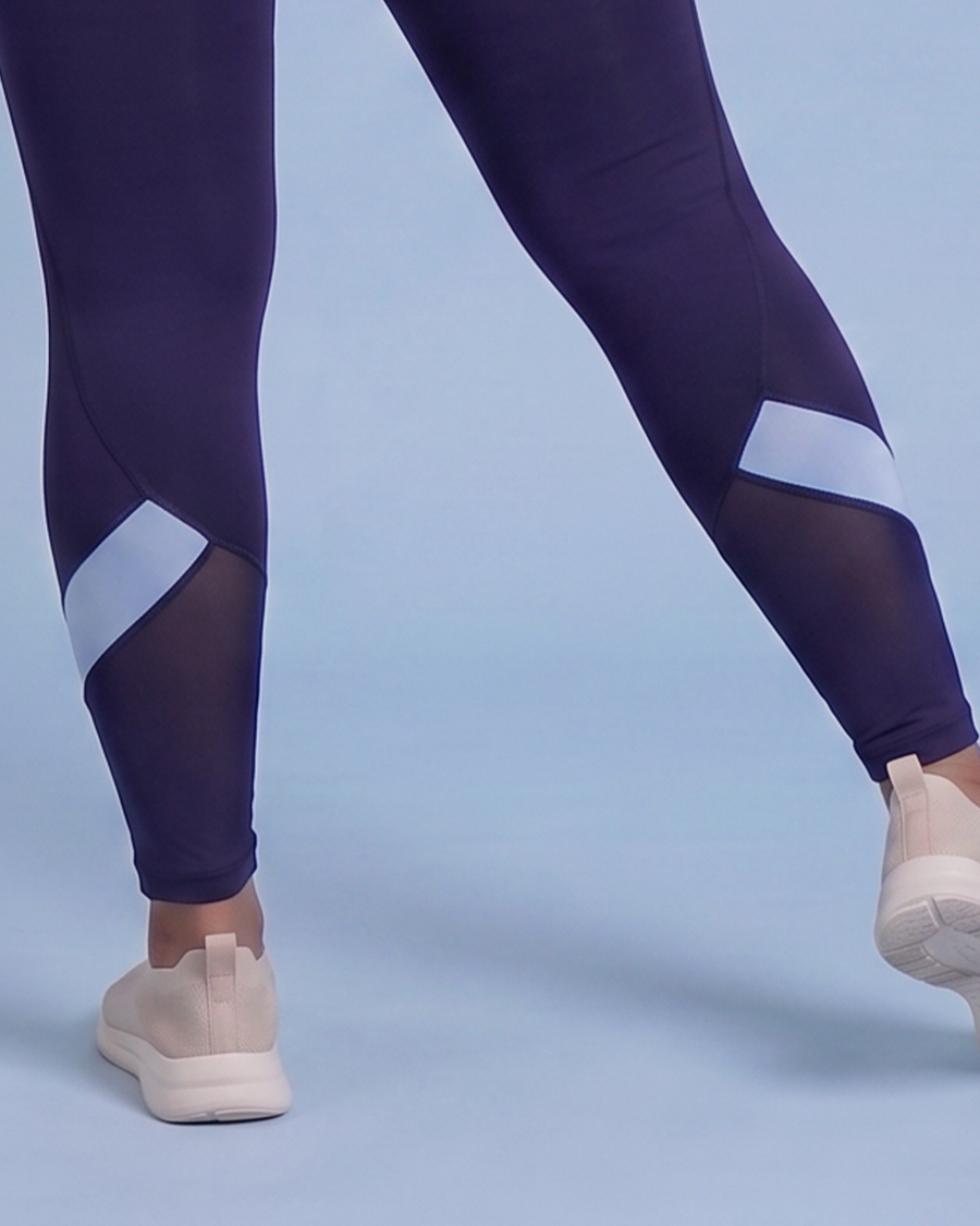 Back view of navy leggings at the calves, showing the mesh panels and light blue contrast panels mid stride.